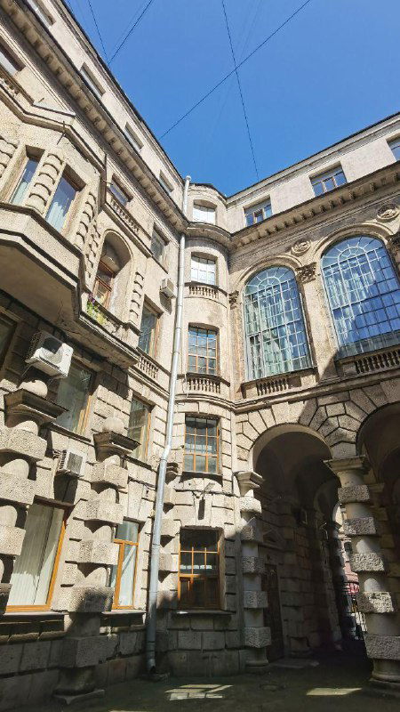 Двор-колодец доходного дома с арками, балконами и окнами — типичный для Петербурга внутренний двор, демонстрирующий планировку и масштаб здания.