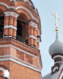 Фрагмент кирпичной колокольни и купола с крестом в Ярославле: декоративная кирпичная кладка и детали купола в крупном плане.