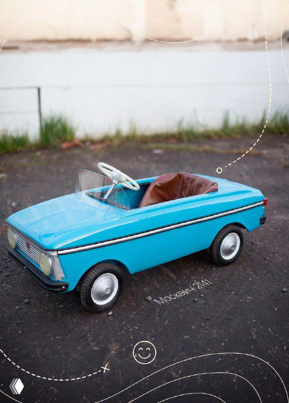 Голубая педальная машина СССР на пустой площадке, крупный план корпуса и руля, видны ретро‑детали и лаковая краска в хорошем состоянии.