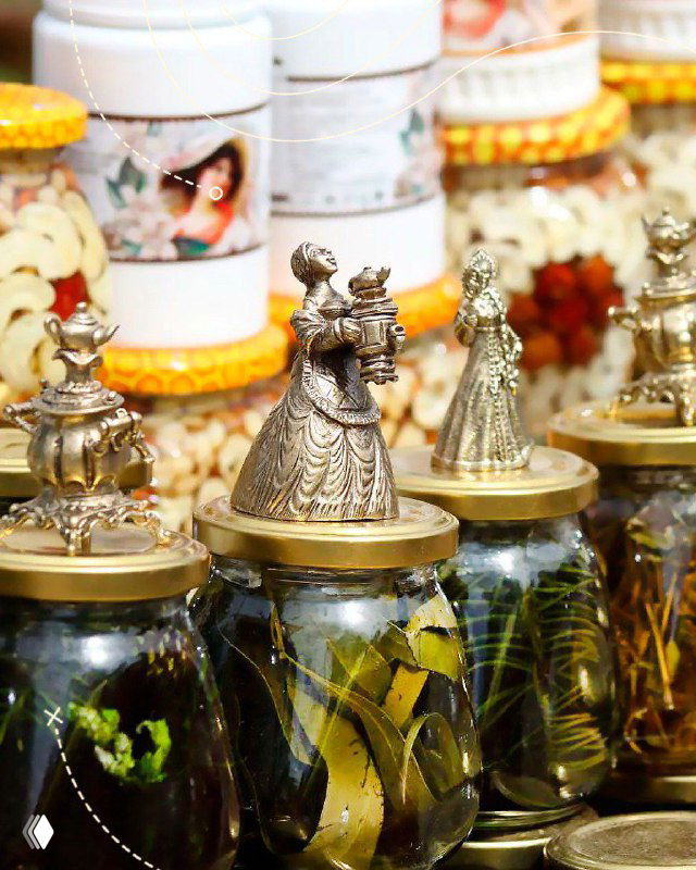 Ряд стеклянных банок с соленьями и небольшими сувенирами на прилавке ярмарки, атмосфера местного рынка и ремесленных лавок фестиваля Крапивы.