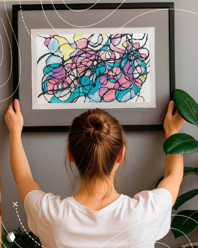 Композиция: человек в интерьерном пространстве развешивает или любуется рамкой с абстрактной картиной, готовой после арт‑сессии.