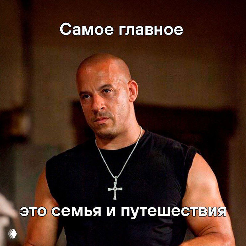 Мужчина в чёрной майке с крестом на шее в интерьере; мем с белыми надписями «Самое главное — это семья и путешествия», атмосферное фото в тёплых тонах