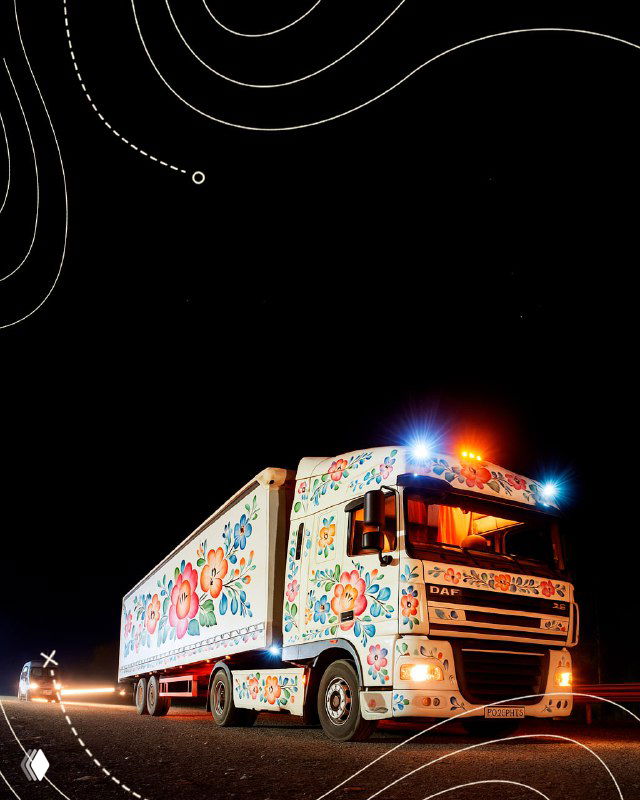 Ночной кадр грузовика, полностью украшенного традиционной росписью Семикаракорска, с включенными фарами и узорами по борту и кабине.