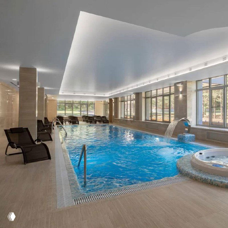 Интерьер современного SPA-центра с большим бассейном, лежаками и панорамными окнами — место релакса после активного дня.