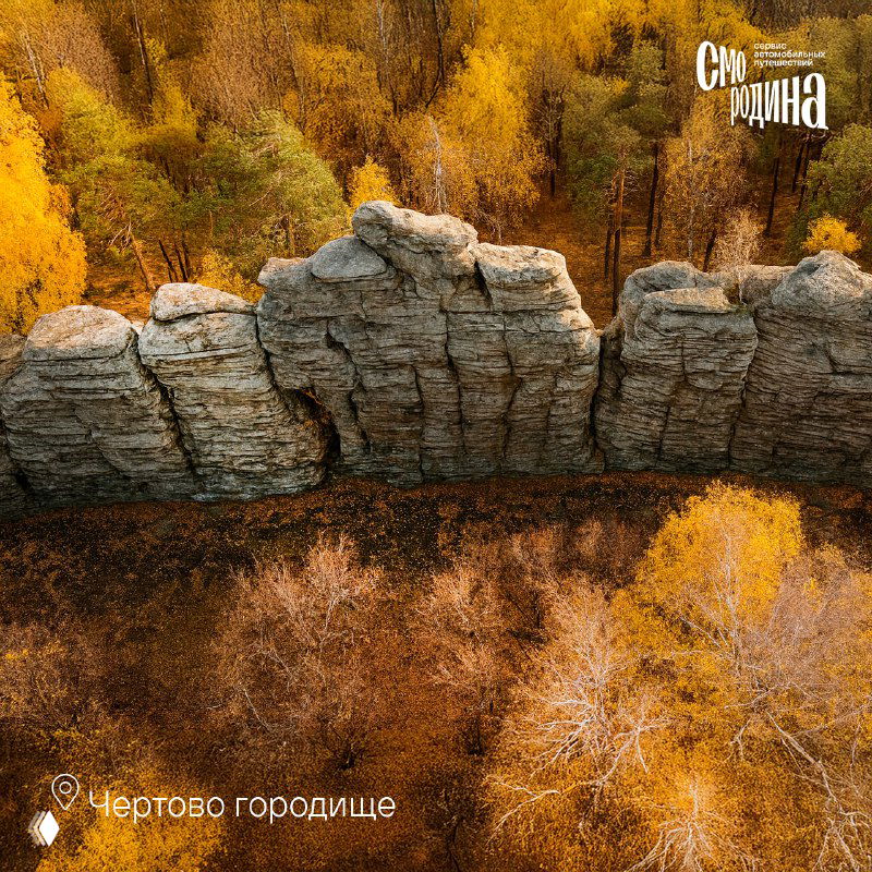 Аэрофотоснимок вытянутой скальной гряды среди осеннего леса — каменные остроги на фоне жёлтой листвы и контрастных теней.