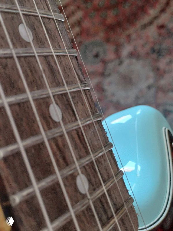 Крупный план грифа и нижней части корпуса Squier Mustang: видны неровные лады, пятна на струнах и фактура накладки.