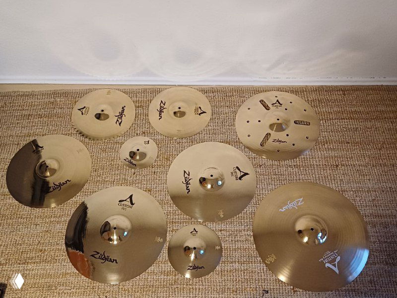 Несколько тарелок и ударных аксессуаров на светлом ковре — набор турецких тарелок, который был выкуплен и упаковывается для доставки