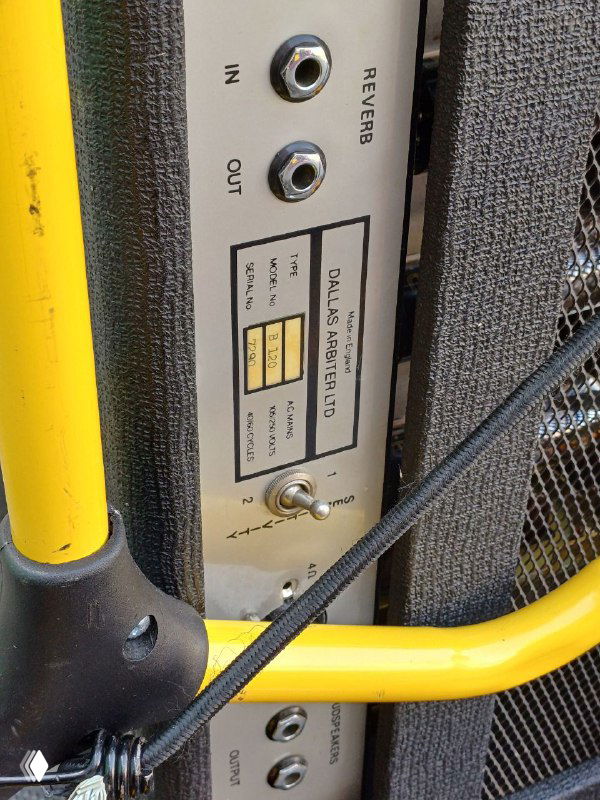 Крупный план боковой панели усилителя Sound City: разъёмы, переключатели и яркая жёлтая защитная рама с видимыми креплениями и текстурами корпуса усилителя.