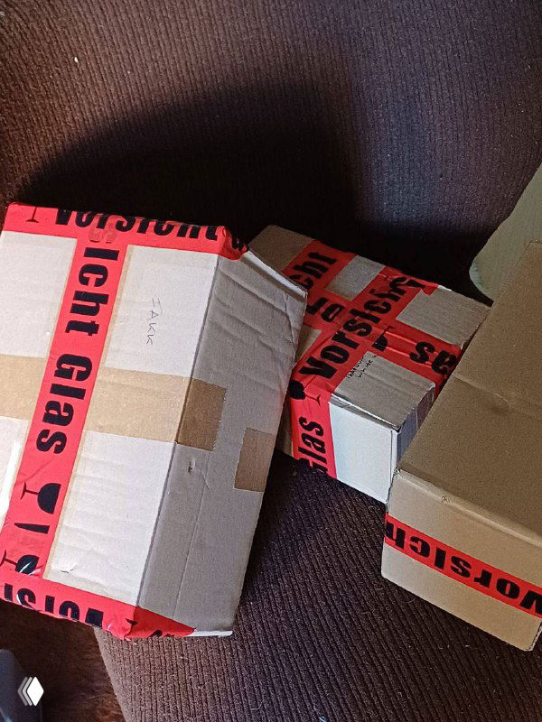 Упакованные картонные коробки с красной лентой «Licht Glas», снимок сверху — иллюстрация подготовки посылок к отправке и логистике.