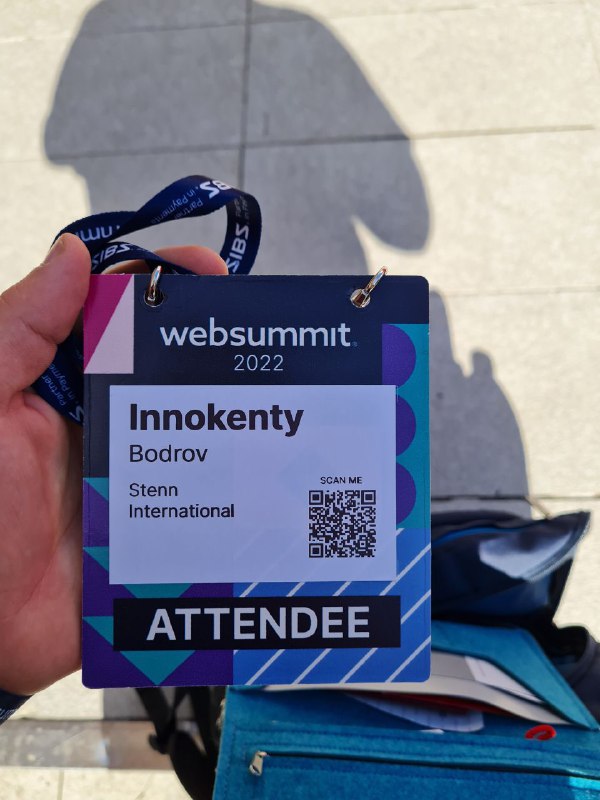 Фотография бейджа участника конференции WebSummit 2022 в руке: виден логотип, надпись WebSummit и слово «ATTENDEE».