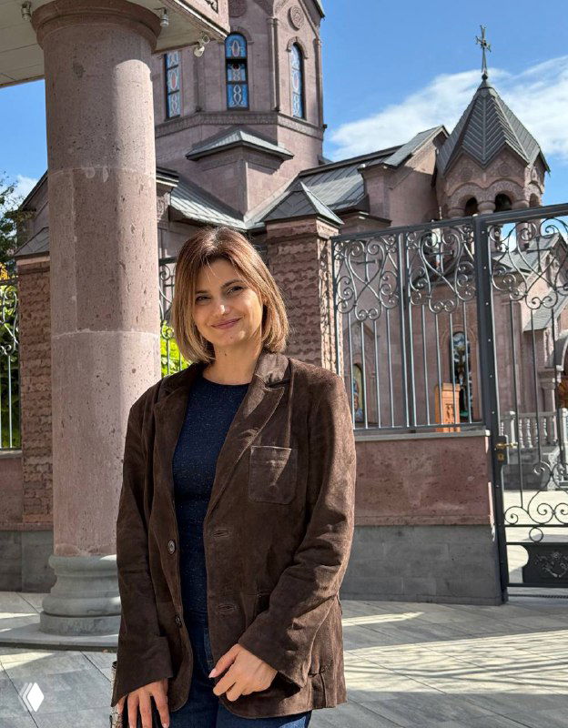 Женщина в коричневом пиджаке стоит на фоне ограды и архитектуры; иллюстрация деловой темы поста о конверсии и работе с аудиторией.