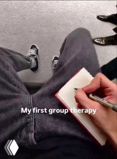 Вид сверху: человек в тёмных штанах делает запись в маленьком блокноте на коленях; на фото видна подпись «My first group therapy», создавая ощущение записей о терапии.