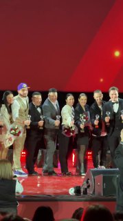 Группа людей на сцене с наградами и цветами, финальный выход участников и победителей мероприятия — общий план завершения церемонии.