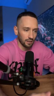 Мужчина в розовом свитере говорит в микрофон в домашней студии; кадр подкаста/видео о маркетинге, продажах и продвижении UDS.