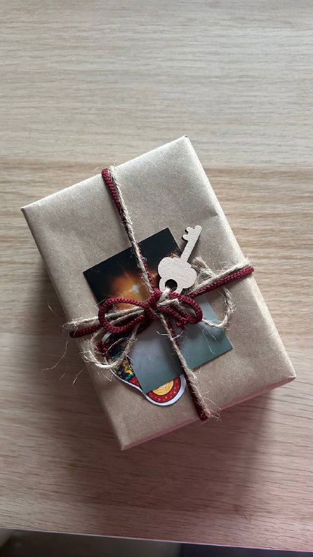 Запакованный набор «Родное Таро» в крафтовой бумаге, перевязанный шнуром с фотокартой и ключевой наклейкой — аккуратная презентация колоды как подарка.