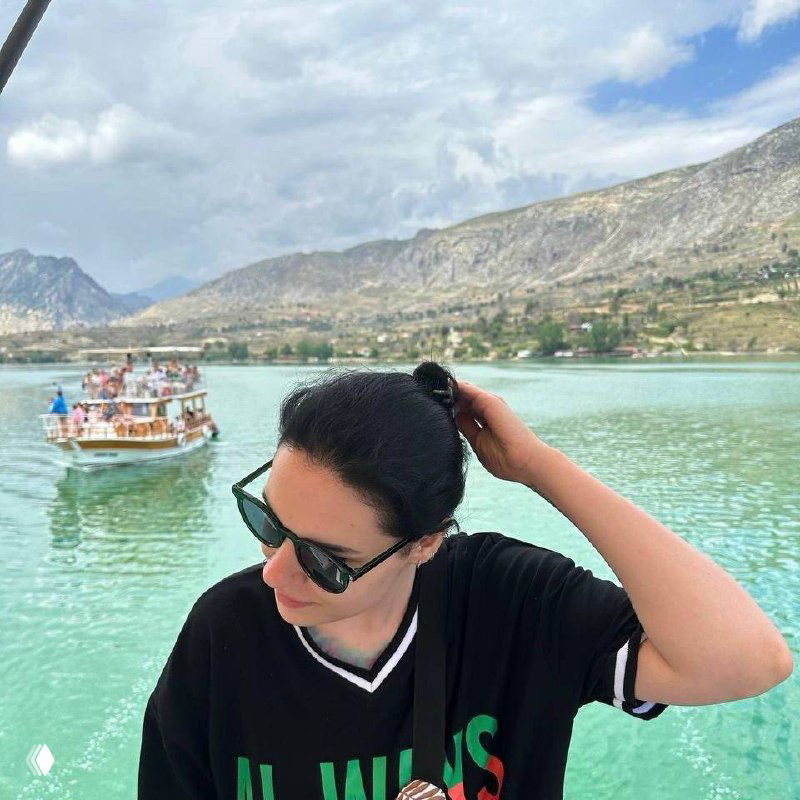 Женщина в солнцезащитных очках у бирюзового озера на фоне гор и лодки, летняя спокойная сцена в профиль, контекст — авторский пост о выборе ориентиров.