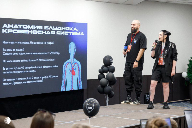 Доклад Тины рядом с экраном, на слайде показана схема «Анатомия бессоницы, кровеносная система», сценическое выступление в конференц-зале.