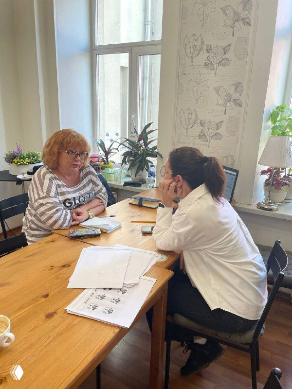 Двое сотрудников обсуждают документы и кандидатов за столом в рамках повышения квалификации по подбору нянь; индивидуальный подход в работе.