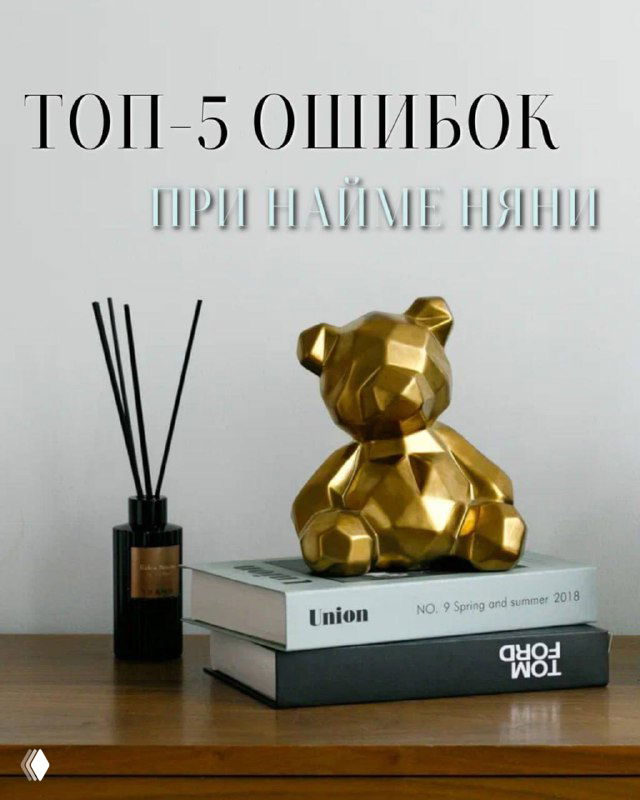 На снимке — золотая геометрическая статуэтка медвежонка на столе рядом с книгами и ароматическим диффузором, светлая стена.