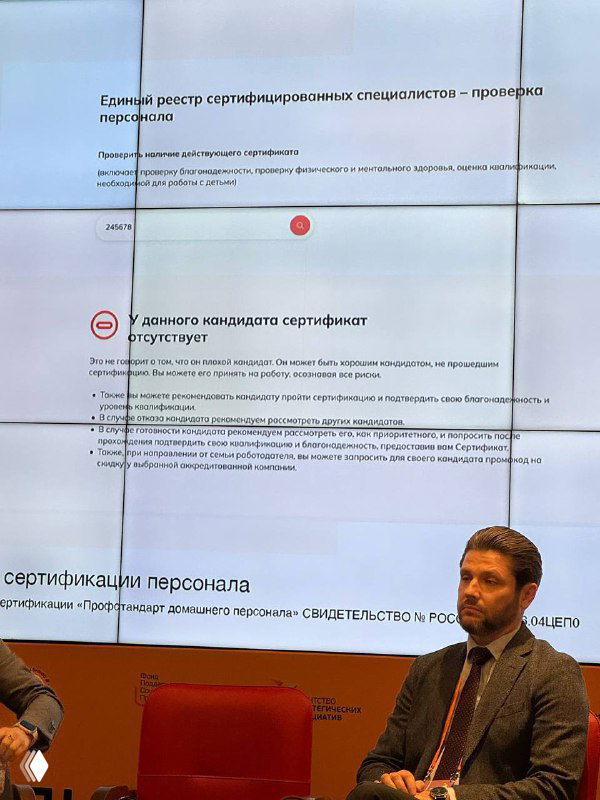 Фото экрана с фрагментами слайда о реестре сертифицированных специалистов; внизу перед экраном сидит выступающий мужчина.