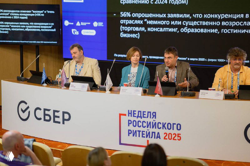 Панель экспертов на Неделе российского ритейла 2025: выступающие за столом, логотип Сбер и баннер «Неделя российского ритейла 2025» на переднем плане.