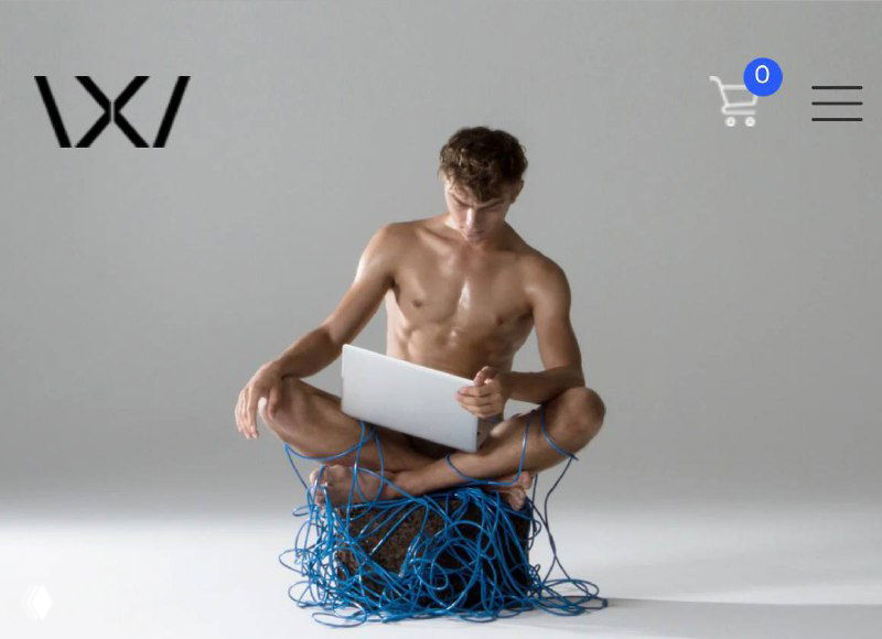 Концептуальная фотография: мужчина сидит с ноутбуком и обвитыми синими проводами, иллюстрируя интеграцию электроники и умной одежды в концепции носимых технологий.