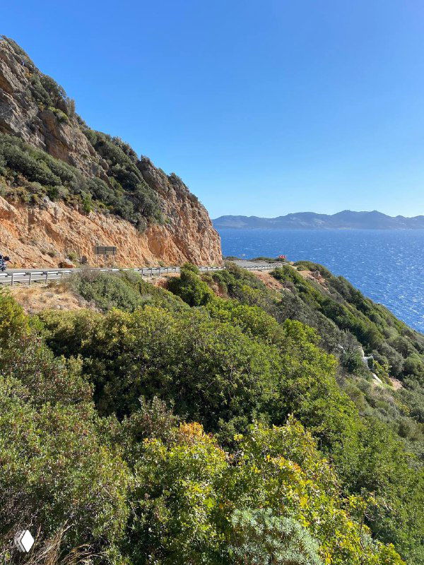 Извилистая прибрежная дорога между скал и кустарников с видом на синее море, типичный пейзаж маршрута из Каша в Калкан.