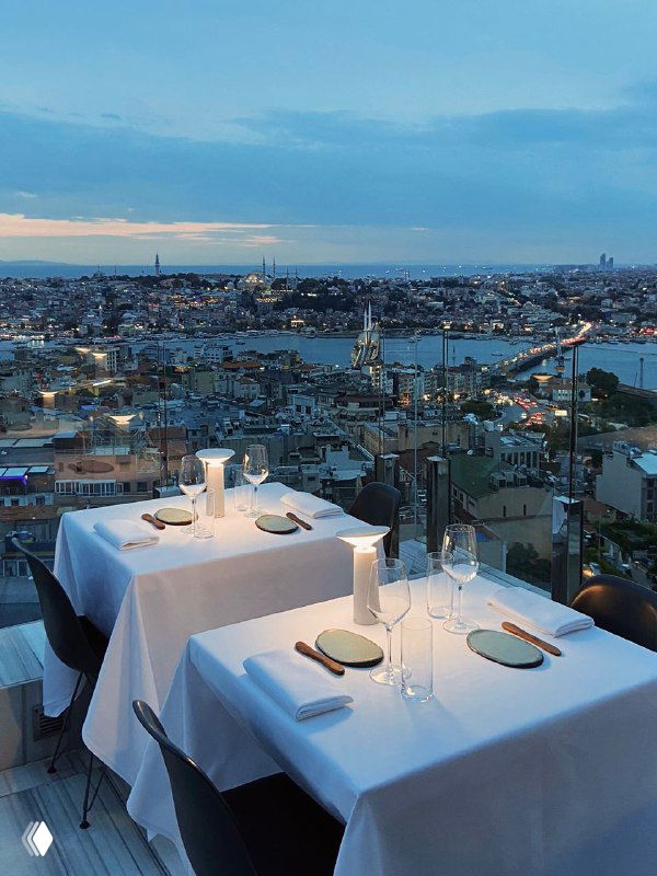 Панорамный вид на Стамбул с высоты: стол на террасе с белой скатертью и широкая панорама города и пролива Босфор на фоне.