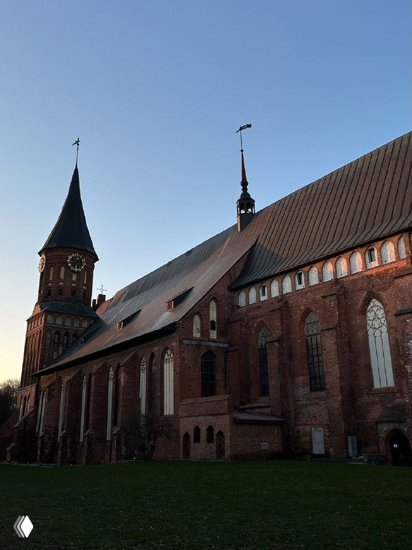 Готический Кафедральный собор на острове Канта в Калининграде: кирпичная кладка, высокий шпиль и мягкое вечернее освещение архитектурного ансамбля.