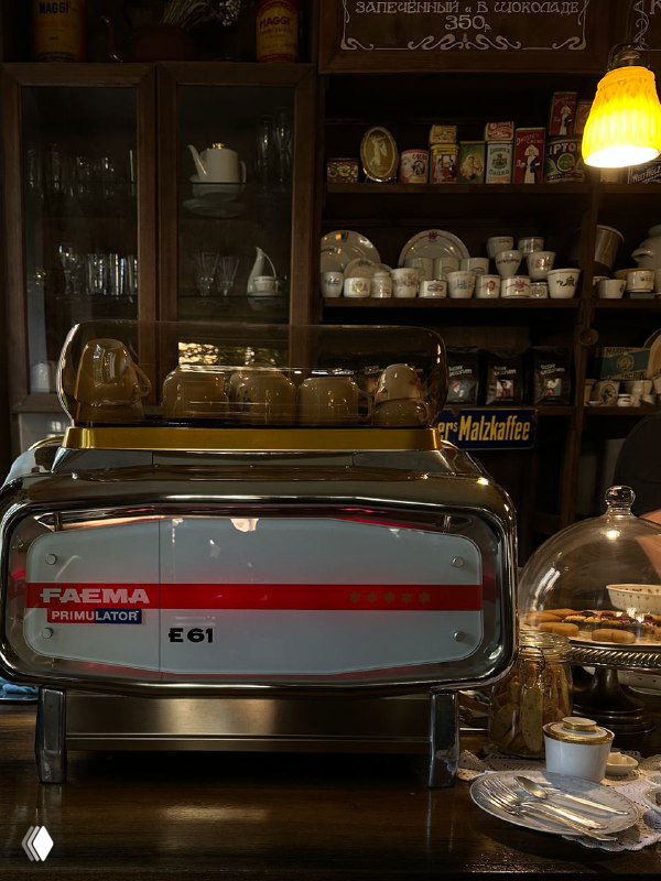 Интерьер кафе в Калининграде с профессиональной эспрессо-машиной, витриной кондитерских изделий и уютной атмосферой, подходящей для завтрака туристов.