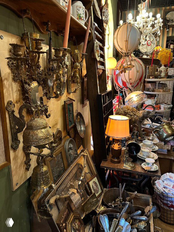 Интерьер антикварной лавки в Калининграде: стеллажи и столы с винтажными предметами, зеркалами, подсвечниками и декоративными элементами для туристов и коллекционеров.