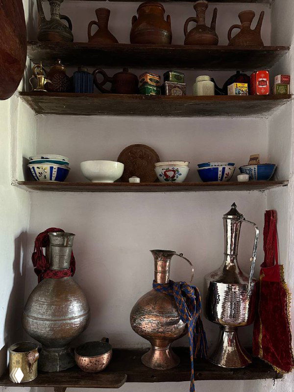 Полки в сакле с традиционной посудой и медной утварью, декоративные миски и бутылочки в аутентичном интерьере дома‑музея.