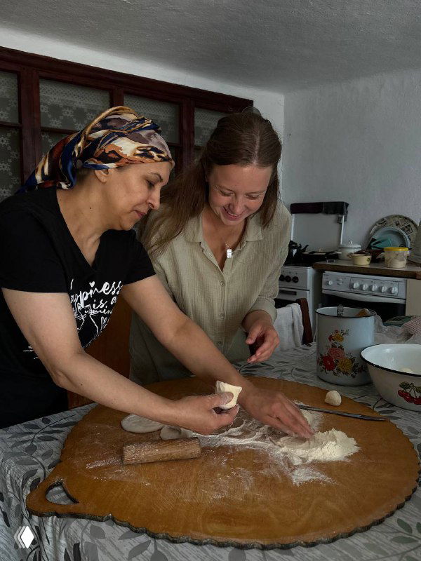 Две женщины готовят тесто на большом столе, традиционная деревенская кухня и процесс лепки аварского чуду в домашних условиях.