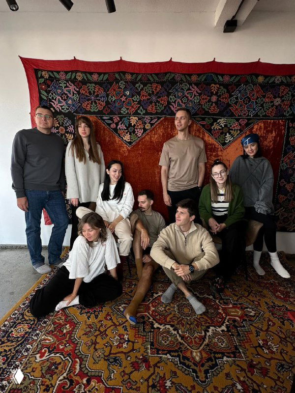 Группа путешественников Tur de Friends в гостеприимном интерьере с национальным ковром и тёплой атмосферой — знакомство с локальной культурой и командой.