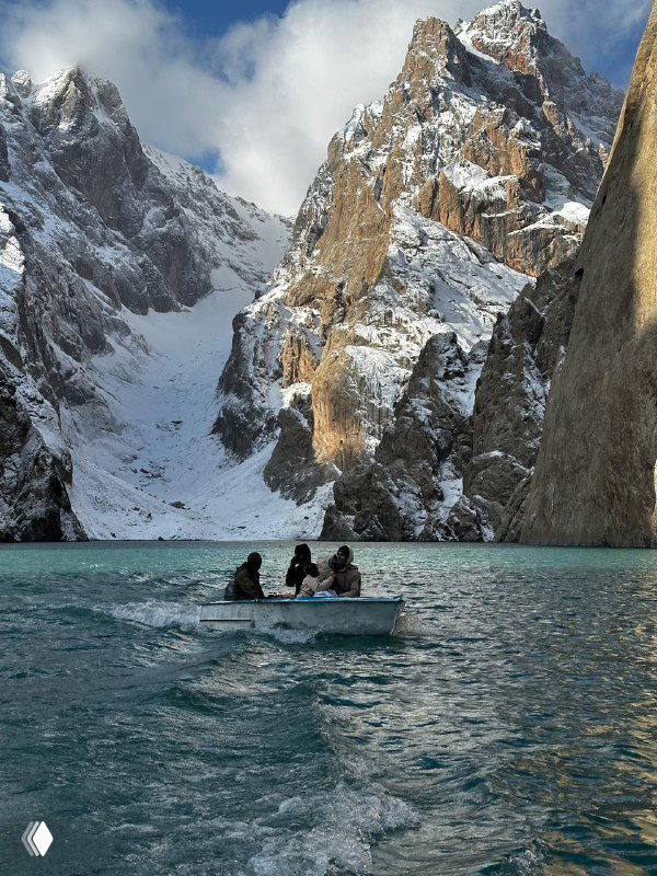 Небольшая лодка на бирюзовом озере в окружении заснеженных пиков Тянь-Шаня — ледниковая вода, ощущение изолированности и первооткрытия.
