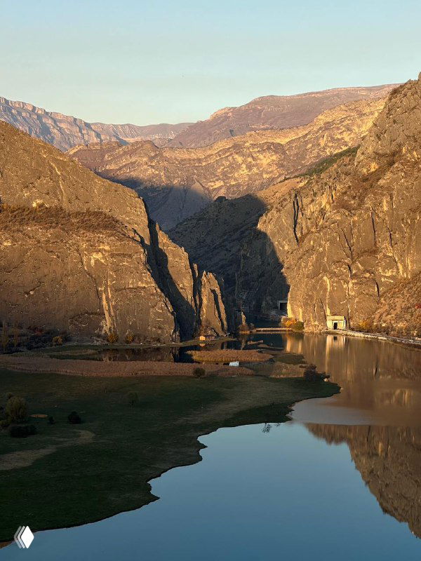 Утреннее озеро в горах Дагестана с отражением скал и мягким осенним светом, почти пустая долина и спокойная вода.