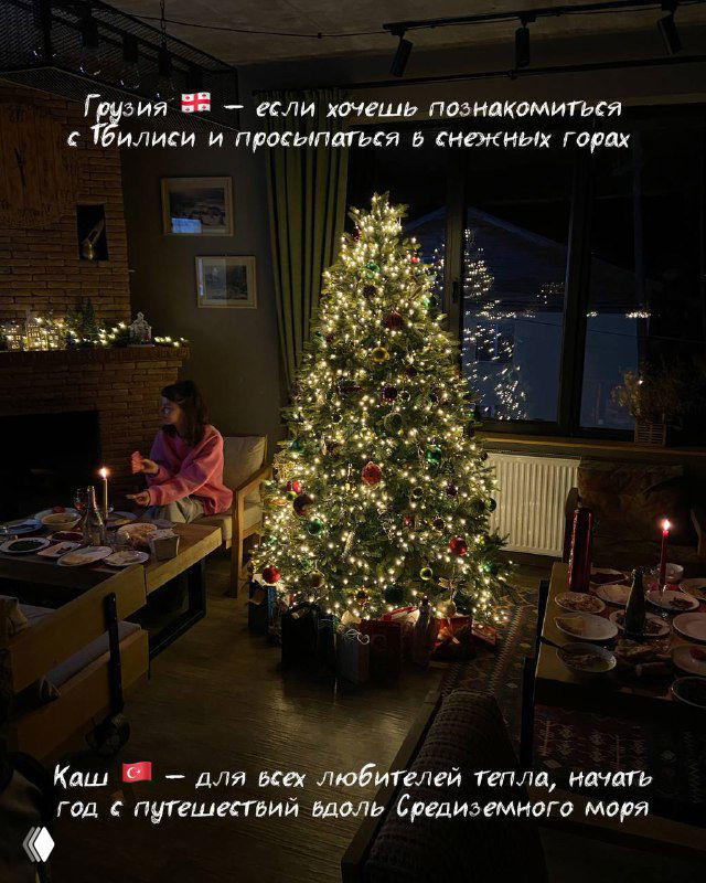 Уютный интерьер с украшенной ёлкой у окна, свечами и видом на заснеженные горы — атмосфера семейного новогоднего путешествия и отдыха.