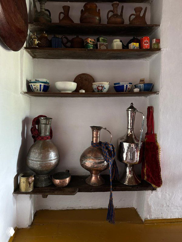 Полка с металлической утварью и аксессуарами традиционного быта — элементы интерьера, показывающие историческую кухню региона.