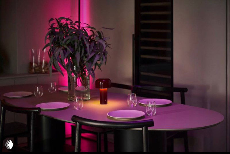 Интимный столик в баре с тарелками и подсвеченной атмосферой розового света — пример новой площадки для апрельского мероприятия.