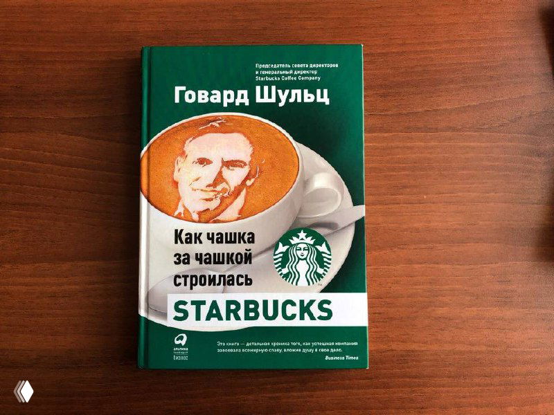Книга Говарда Шульца «Как чашка за чашкой строилась Starbucks» на столе, видна обложка с логотипом сети кофеен.