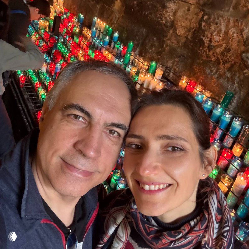 Селфи автора с Андреем перед стеной с зажжёнными разноцветными свечами внутри священного пространства Монсеррат, улыбки на лицах пары.