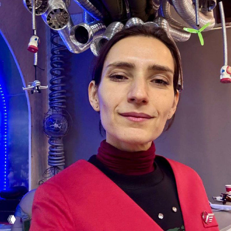 Портрет автора в клубе «Авиатор»: женщина на фоне авиационных декораций, тренажёров и металлических деталей, тёплый портрет.