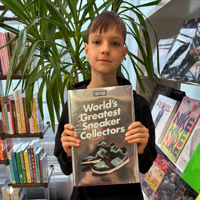 Ребёнок в музее «Гараж» держит книгу про коллекционеров кроссовок — кадр внутри выставочного и книжного пространства.