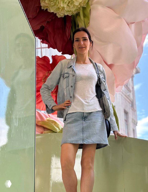 Автор поста позирует рядом с крупной цветочной инсталляцией и декоративными элементами — часть уличного оформления летней экспозиции.