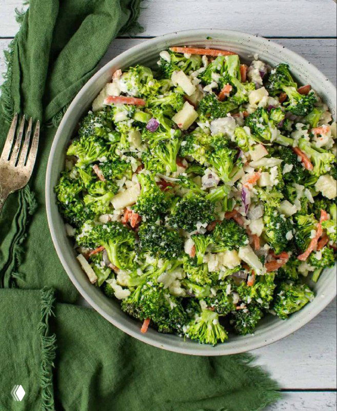 Тарелка со свежим салатом из брокколи и цветной капусты с морковью и зеленью на светлом деревянном фоне, домашняя праздничная подача.