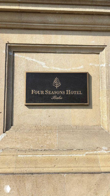 Табличка отеля Four Seasons Baku на каменной стене, крупный план вывески, лаконичная идентификация места проживания и гостиничная эстетика