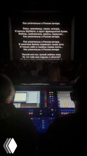 Рабочая панель звукорежиссуры и фрагмент проекции текста на сцене, вид с технического пульта внизу зала