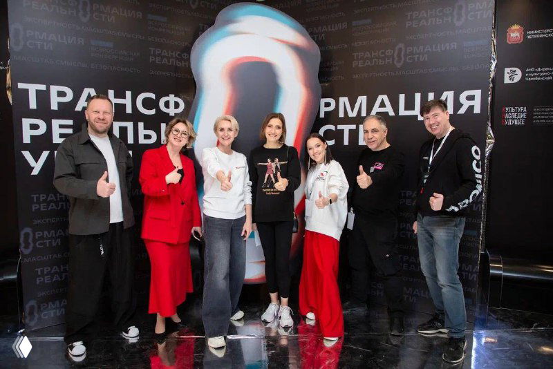 Группа организаторов и участников стоит на фоне бренд‑волла форума, в кадре команда и позитивная атмосфера встречи.