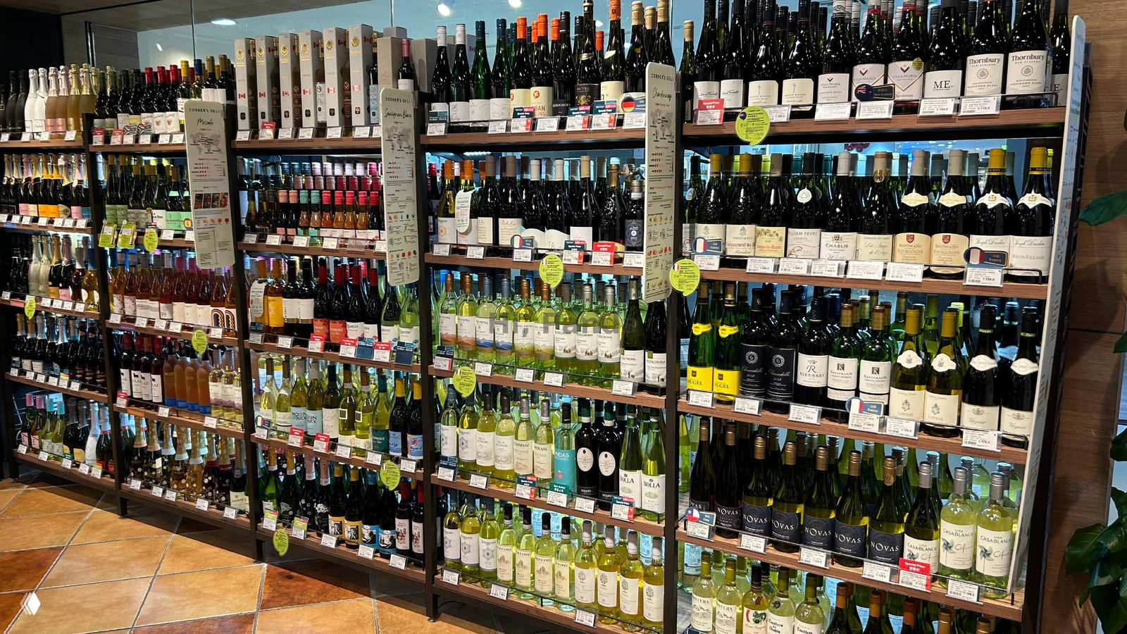 Широкие полки с большим ассортиментом вин и крепких напитков в винном отделе магазина ТЦ «Лето», видны разнообразные бутылки, ценники и этикетки.
