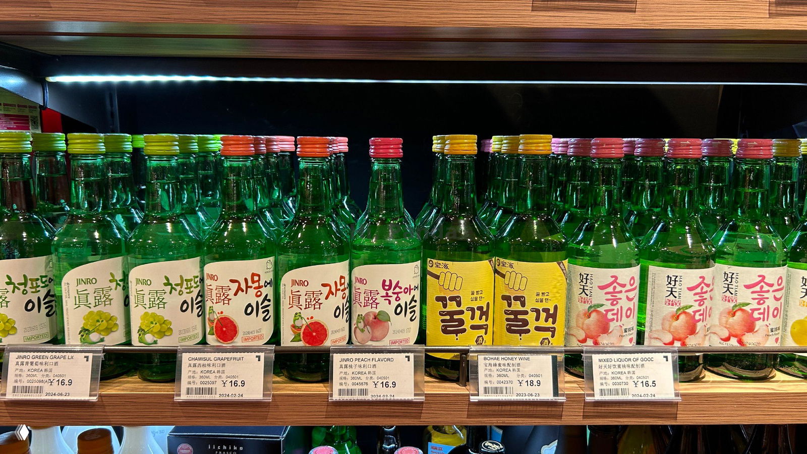 Проход магазина с плиточным полом и рядами полок, видна витрина с алкоголем и общий интерьер отдела напитков в торговом центре.